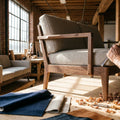 A skilled craftsman works on a modern sofa frame inside a bright, well-equipped American furniture workshop with natural light and quality materials visible throughout.