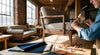 A skilled craftsman works on a modern sofa frame inside a bright, well-equipped American furniture workshop with natural light and quality materials visible throughout.